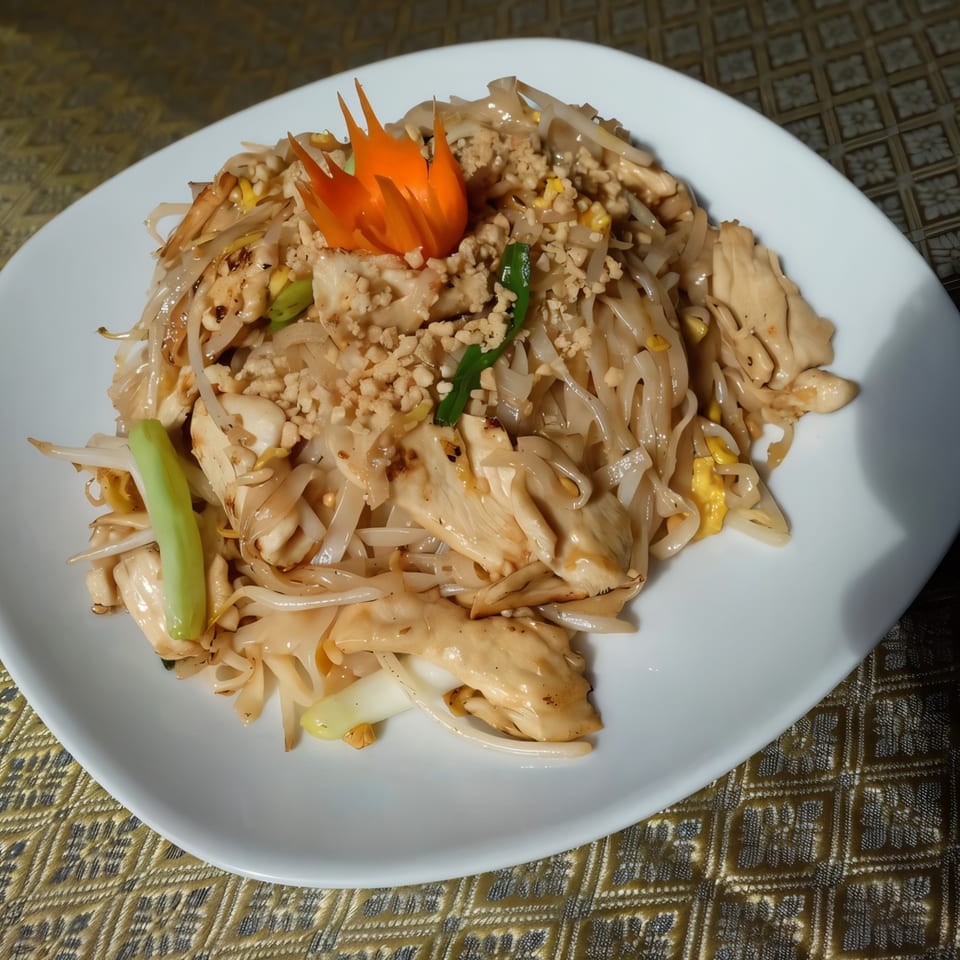 Thai Nakornping's Pad See Ew with chicken, wide noodles, and a carved carrot garnish.