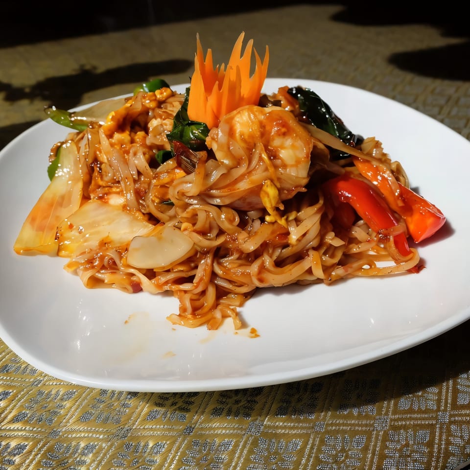 Thai Nakornping's Pad Kee Mao with shrimp, wide noodles, vegetables, and a carved carrot garnish.