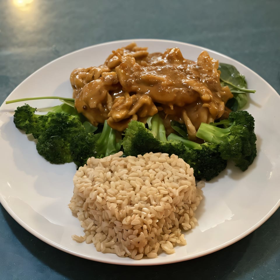 Thai peanut chicken with broccoli, spinach, and brown rice on a white plate.